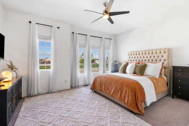 Large room with multiple windows, a ceiling fan with integrated lighting, and carpet flooring