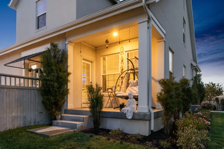 Covered porch with concrete steps, a privacy fence, and mature landscaping