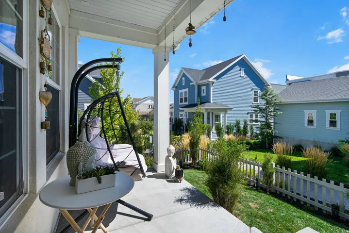 Concrete front porch with white columns, white railings, and a manicured lawn with a picket fence