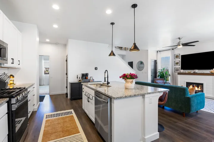 Open-concept kitchen featuring an island with integrated sink, stainless steel appliances, and white cabinetry