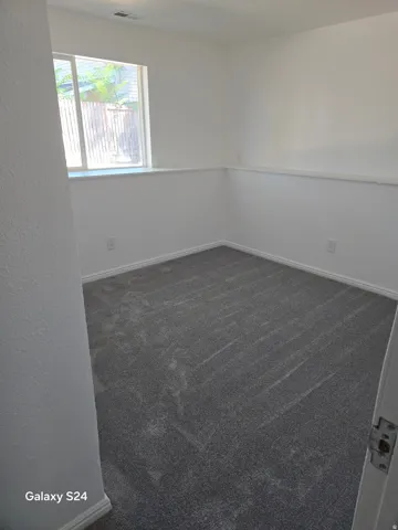 Gray carpeted flooring, white painted walls, and a large window