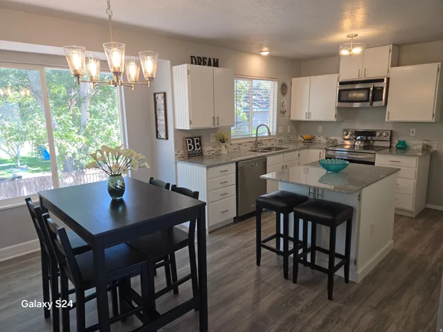 Kitchen featuring wood-finish flooring, white cabinetry, a built-in kitchen island, and stainless steel appliances