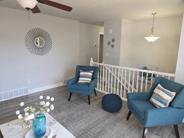 Wood-finish flooring, white trim, and a ceiling fan with light fixture