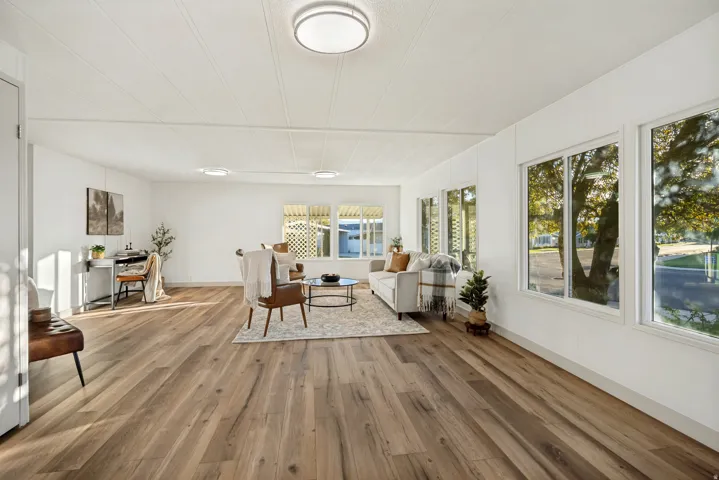 Expansive open-concept room featuring wood-finish flooring, white walls, and multiple windows