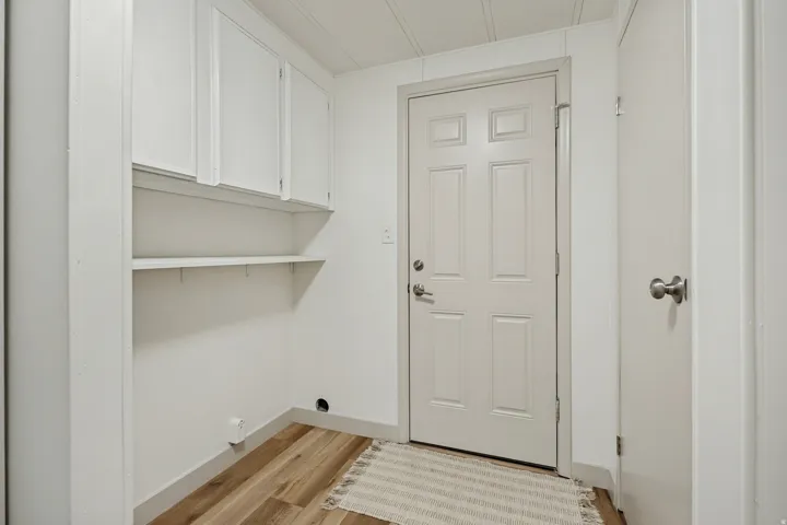 Wood-finish flooring with white wall paneling, built-in cabinetry, and integrated shelving