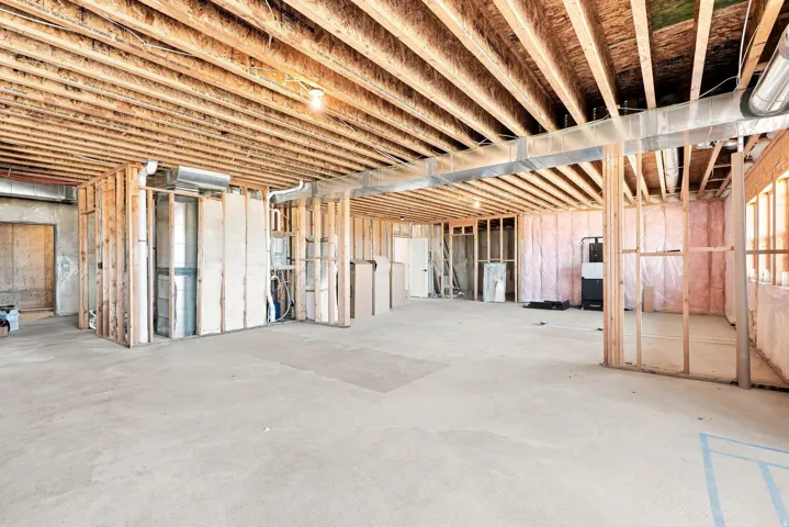 Unfinished lower level with exposed ceiling joists, concrete flooring, and partial framing