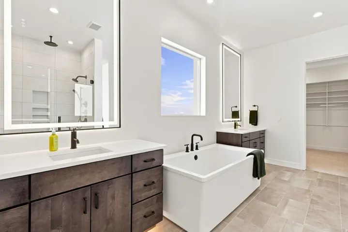 Freestanding soaking tub, dual vanity with undermount sinks, matte black fixtures, and a glass-enclosed shower