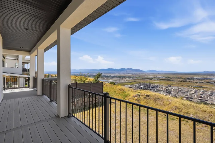 Expansive balcony with composite decking, black metal railing, and a distant mountain backdrop