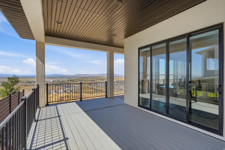Expansive covered deck featuring composite decking, black metal railings, and a multi-panel sliding glass door