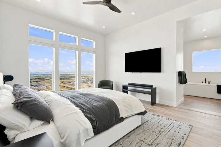 Expansive window wall, recessed lighting, ceiling fan, wood-finish flooring, and built-in soaking tub