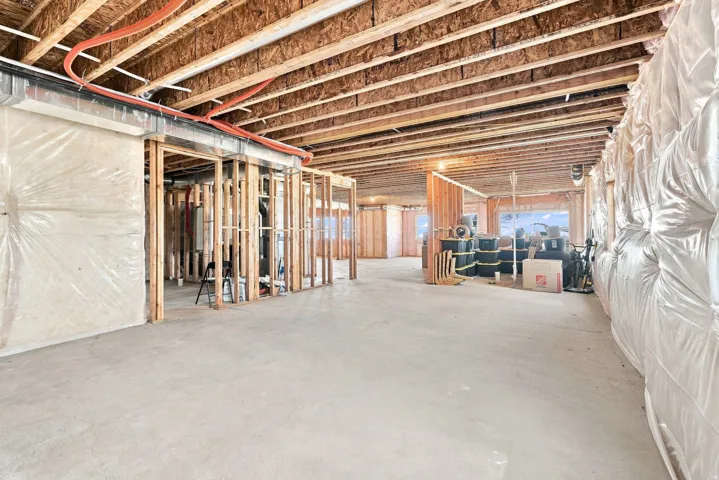 Unfinished lower level with concrete flooring, exposed ceiling joists, and structural framing