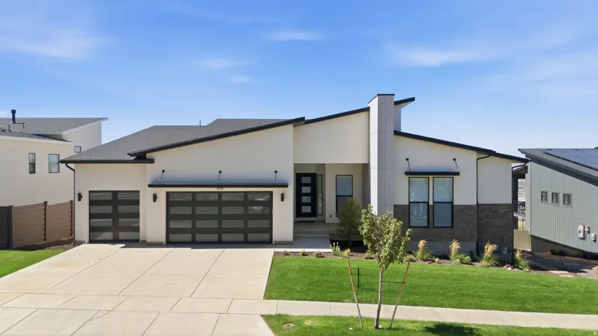 Modern exterior featuring a prominent black roofline, white stucco siding, and stone accents