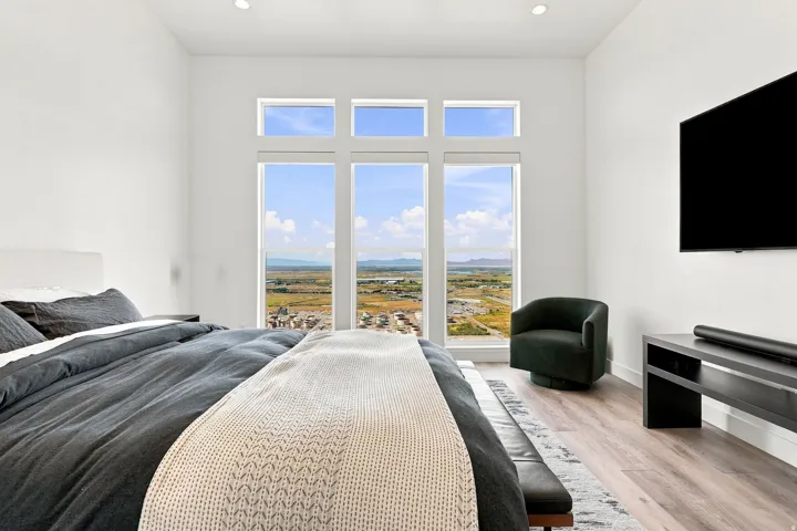 Floor-to-ceiling windows, wood-finish flooring, recessed lighting, and a wall-mounted television