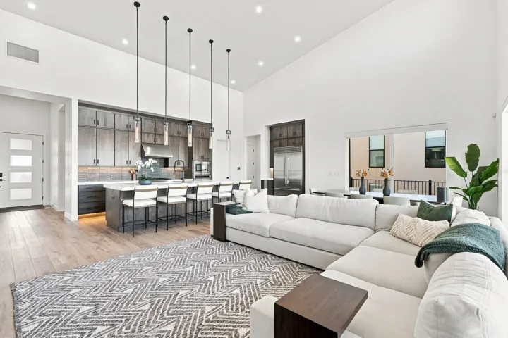 Vaulted ceilings with recessed lighting, wood-finish flooring, kitchen island with seating, stainless steel appliances, and sleek pendant lighting