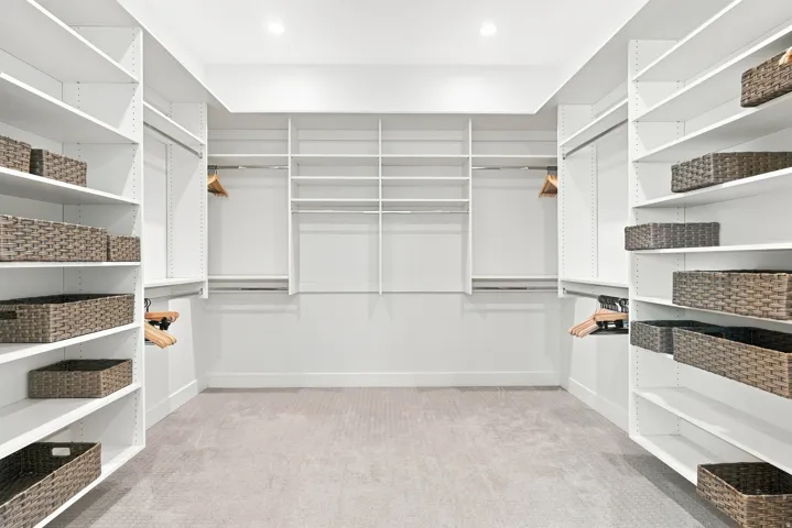 Walk-in closet with extensive built-in shelving, multiple hanging rods, and recessed lighting