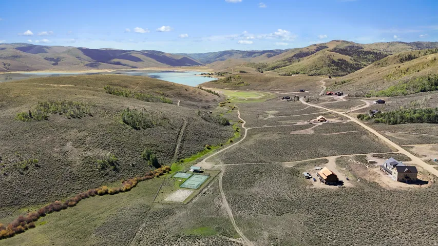 Expansive natural landscape with rolling hills, a large body of water, and residential structures