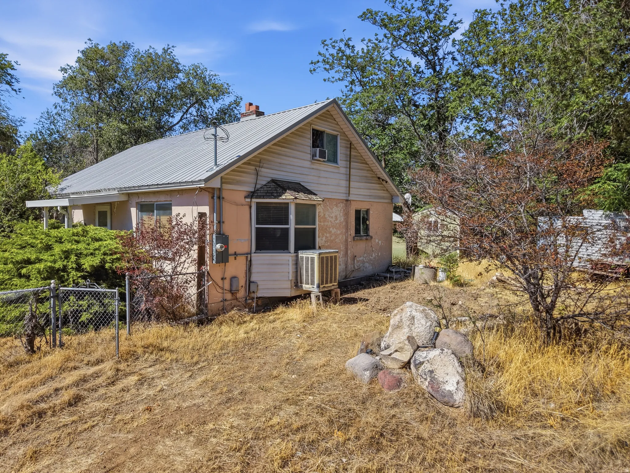 Property exterior featuring a metal roof, dormer window, and chain-link fencing