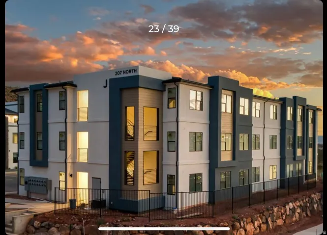 Modern multi-story building featuring a white and dark gray exterior with wood-finish paneling accents