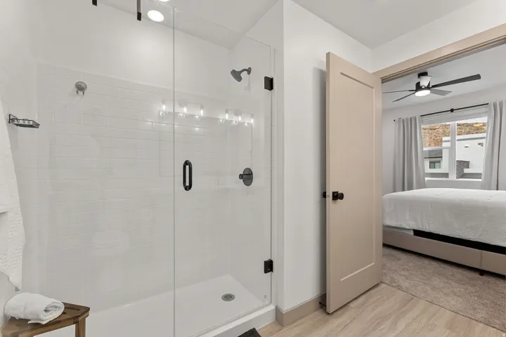 Glass-enclosed shower with subway tile surround, white shower pan, and matte black fixtures