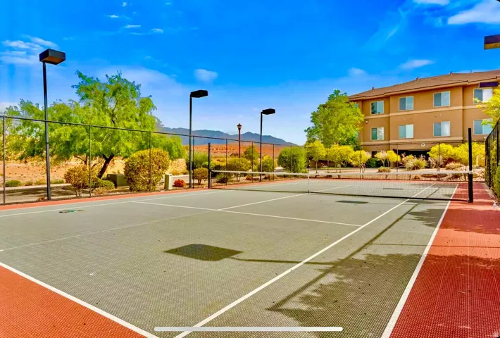 Resurfaced tennis court with perimeter fencing, integrated lighting, and surrounding landscaping
