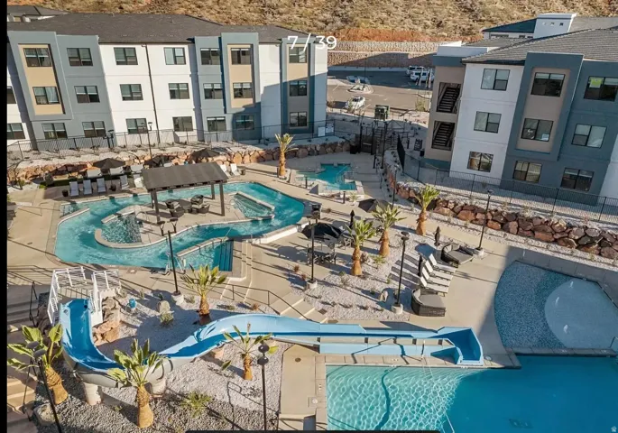 Resort-style pool area featuring a lazy river, water slide, and multiple seating areas