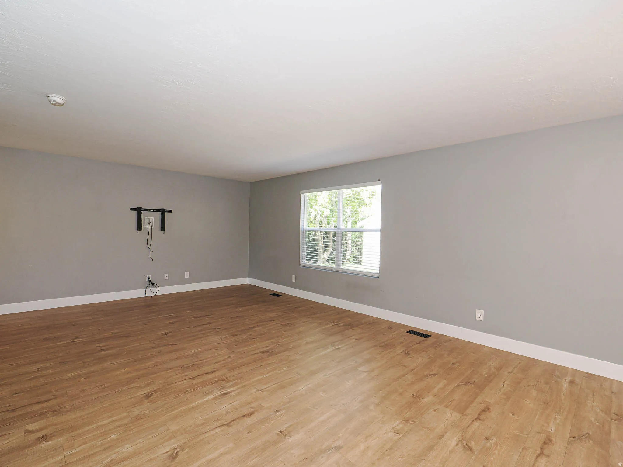 Wood-finish flooring, light gray walls, white trim, and a window with blinds