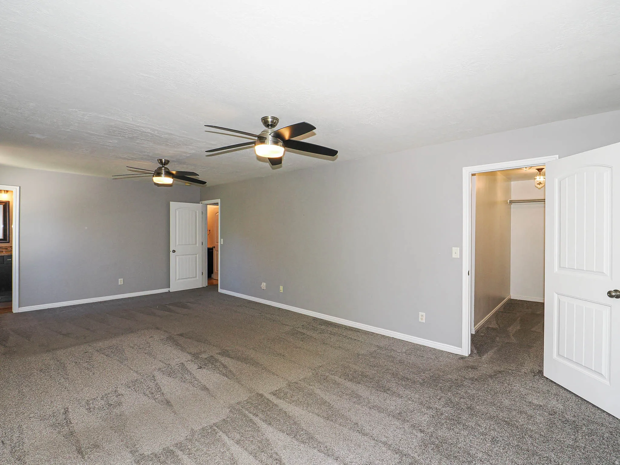 Spacious room with gray carpeting and light gray wall paint