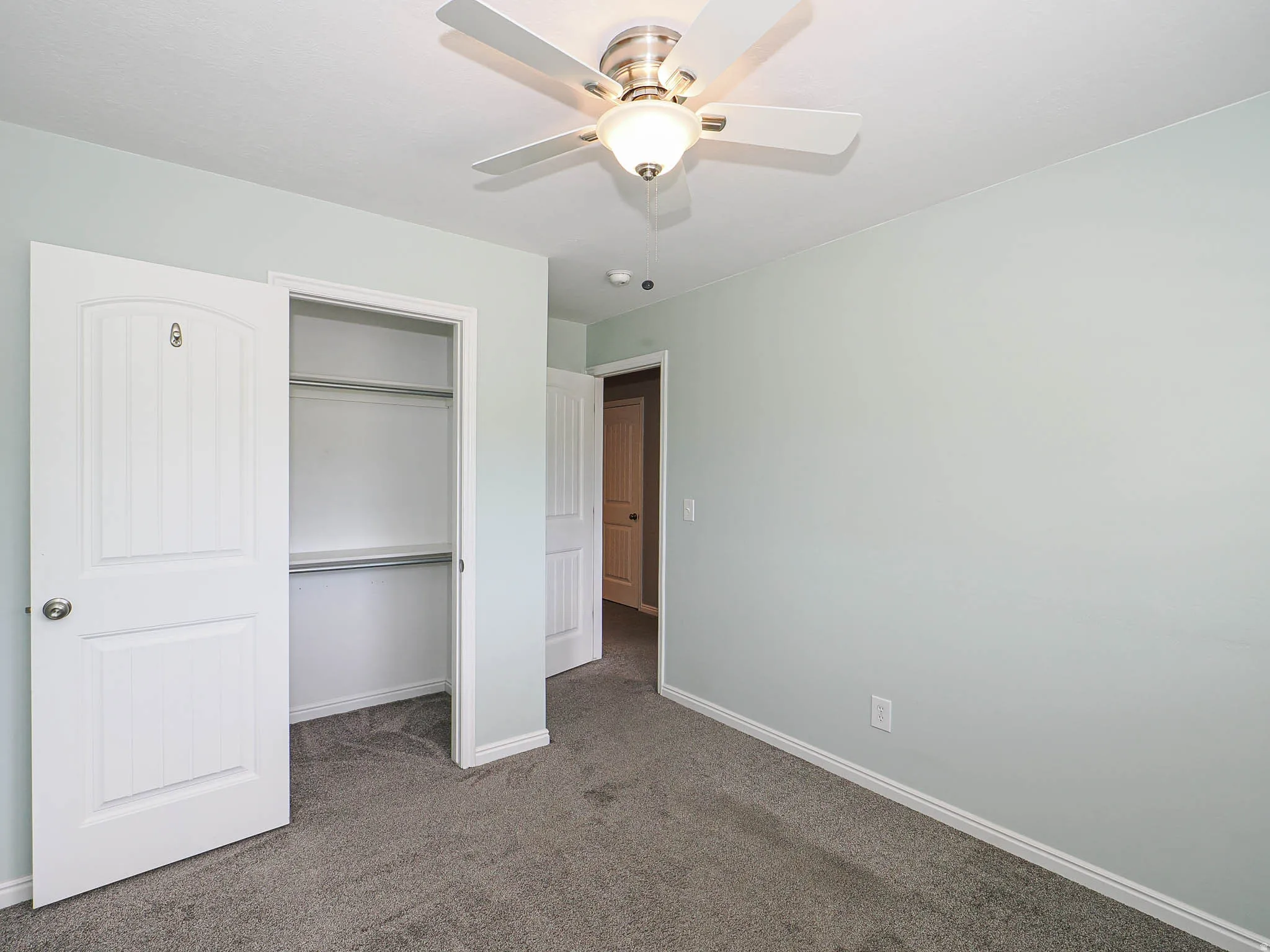 Recessed closet with shelving and hanging rods, ceiling fan with integrated lighting, and carpeted flooring