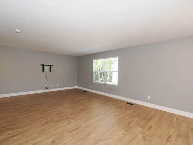Wood-finish flooring, light gray walls, white trim, and a window with blinds