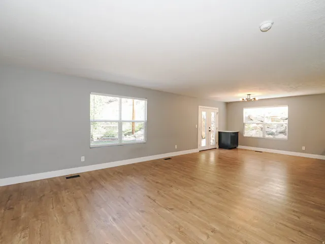 Expansive room featuring wood-finish flooring, light gray walls, multiple windows, and a ceiling-mounted light fixture