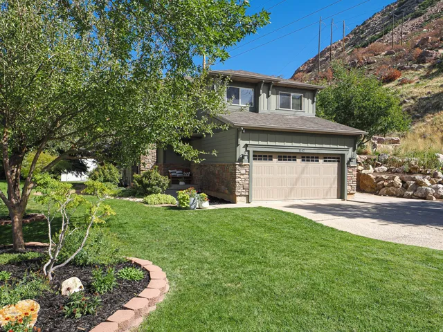 Stone and siding exterior with a light-colored garage door, complemented by a concrete driveway and a manicured lawn