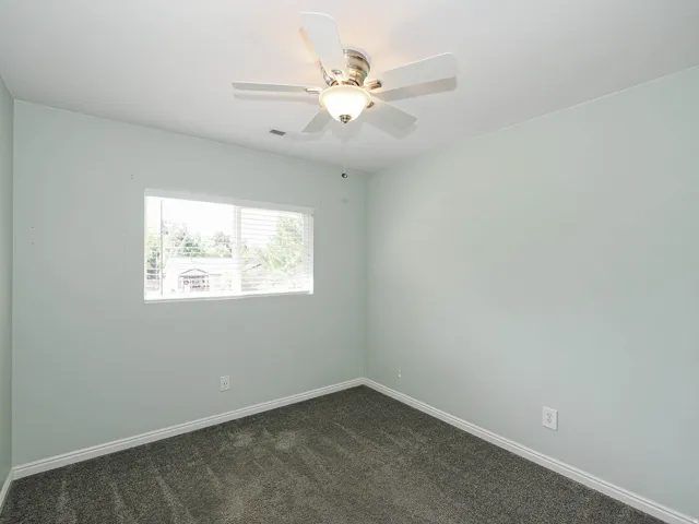 Window with blinds, ceiling fan with integrated lighting, and carpeted flooring