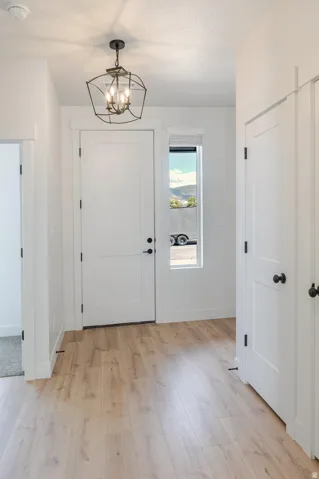 Wood-finish flooring, white paneled doors, and a decorative pendant light fixture