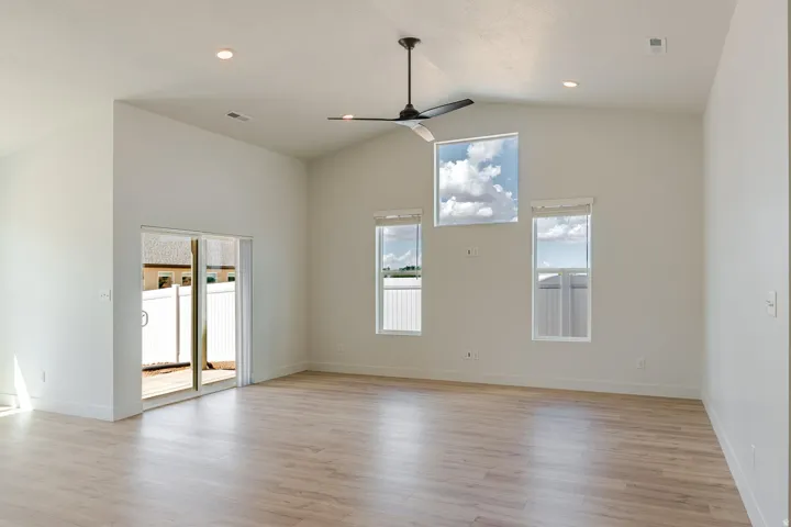 Vaulted ceilings, wood-finish flooring, recessed lighting, ceiling fan, and sliding glass door to exterior