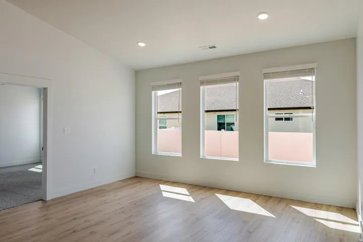 Wood-finish flooring, recessed lighting, and three large windows with blinds