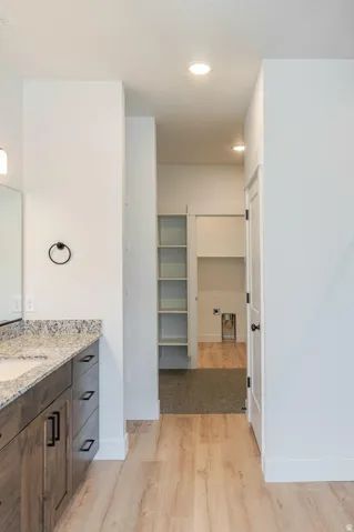 Wood-finish flooring with a stone-finish countertop vanity, featuring dark wood cabinetry and black hardware