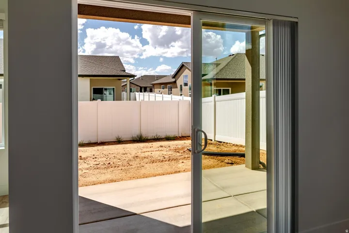Sliding glass door opening to a concrete patio and private fenced backyard