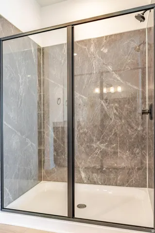 Enclosed shower with sliding glass doors, dark-framed fixtures, and a white shower pan