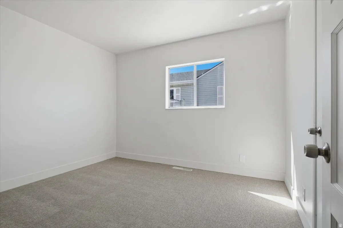 Light gray carpeting, a single window, and a white interior door