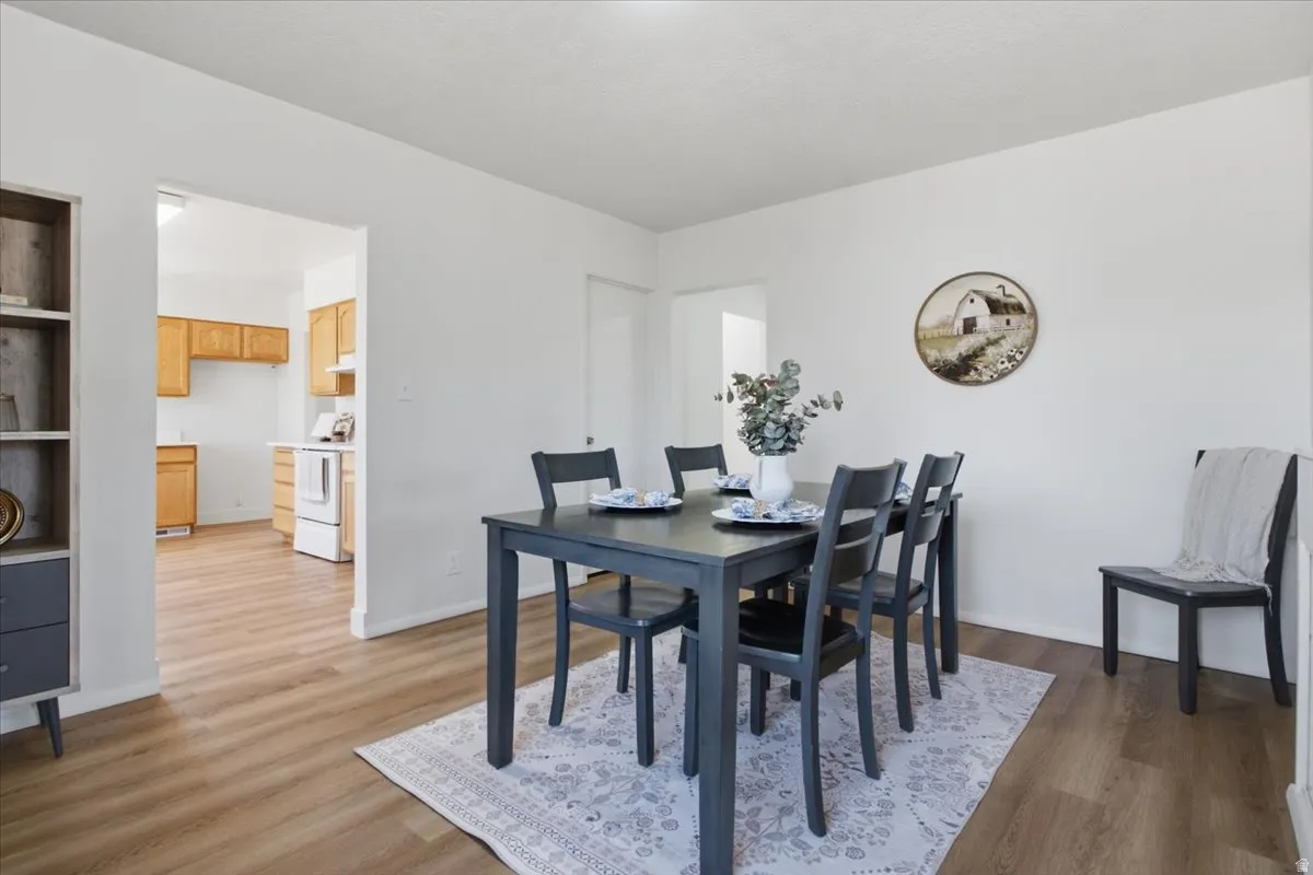 Wood-finish flooring throughout, bright white walls, and a recessed doorway leading to the kitchen