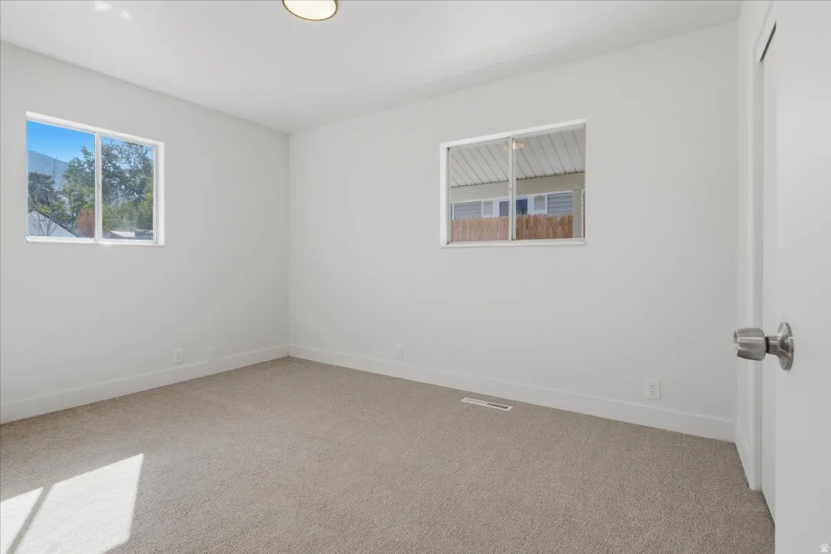 Plush carpeting, bright white walls, and two distinct windows