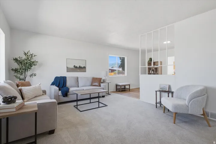 Vaulted ceiling, recessed lighting, expansive carpeted flooring, wood-finish flooring, and a decorative room divider