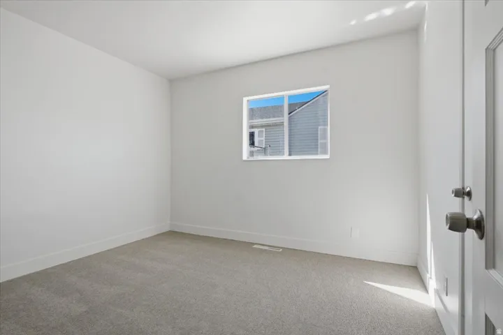 Light gray carpeting, a single window, and a white interior door