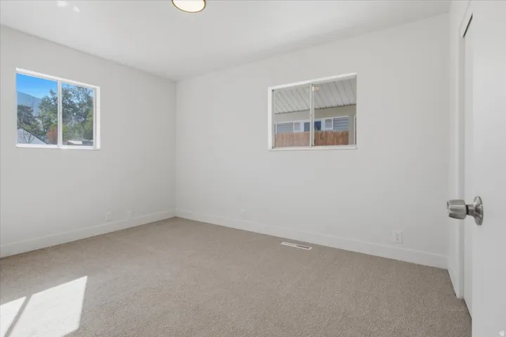 Plush carpeting, bright white walls, and two distinct windows