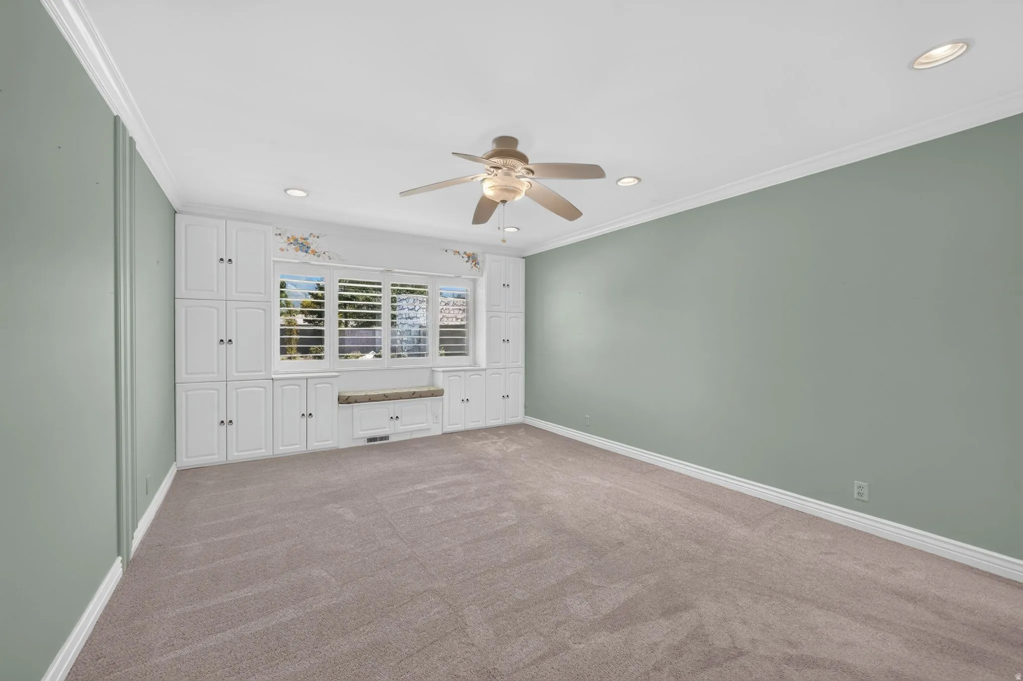 Built-in cabinetry with window seating, plantation shutters, recessed lighting, and a ceiling fan