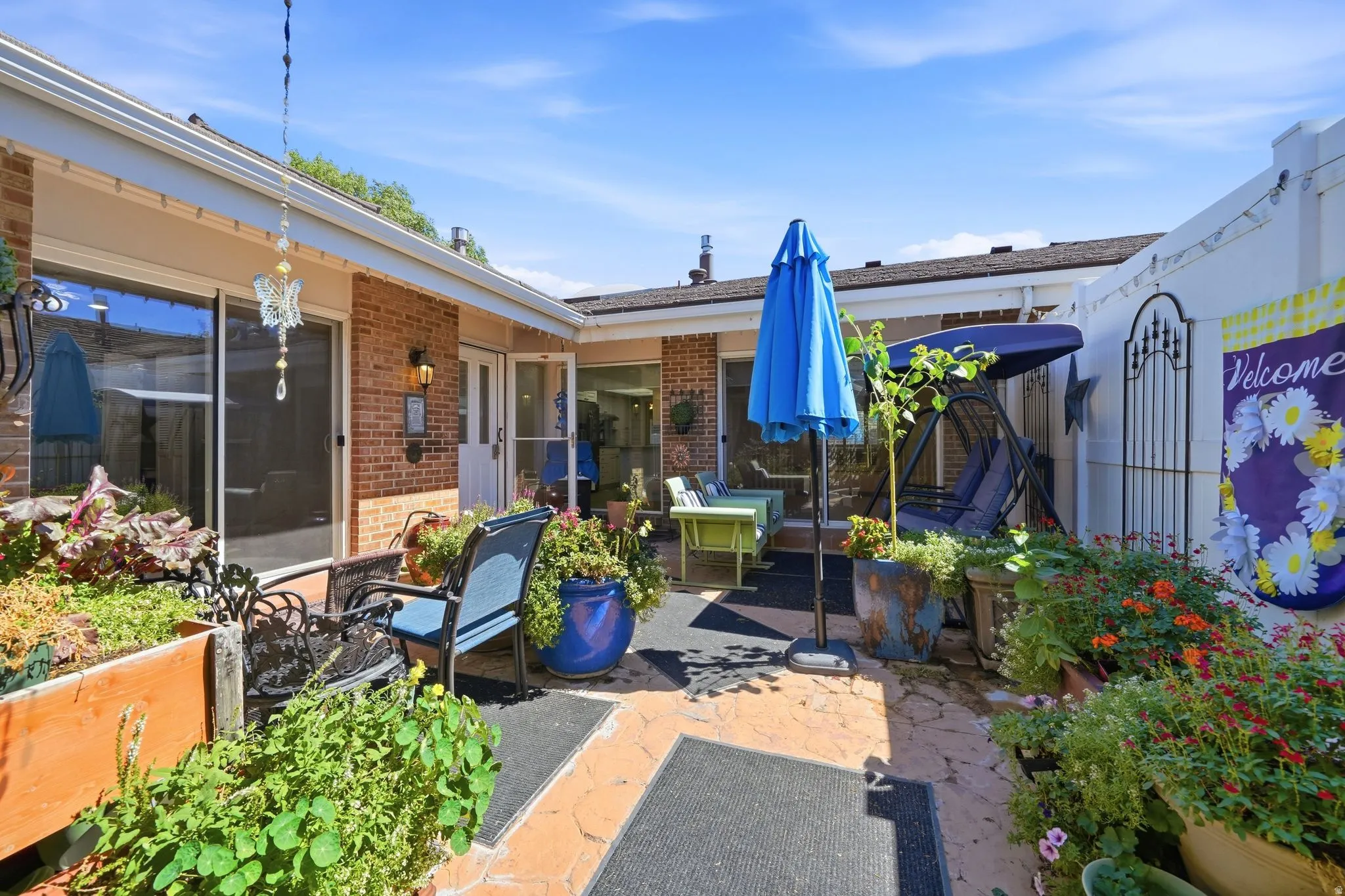 Enclosed courtyard featuring brick siding, a sliding glass door, a privacy fence, and a paved patio area