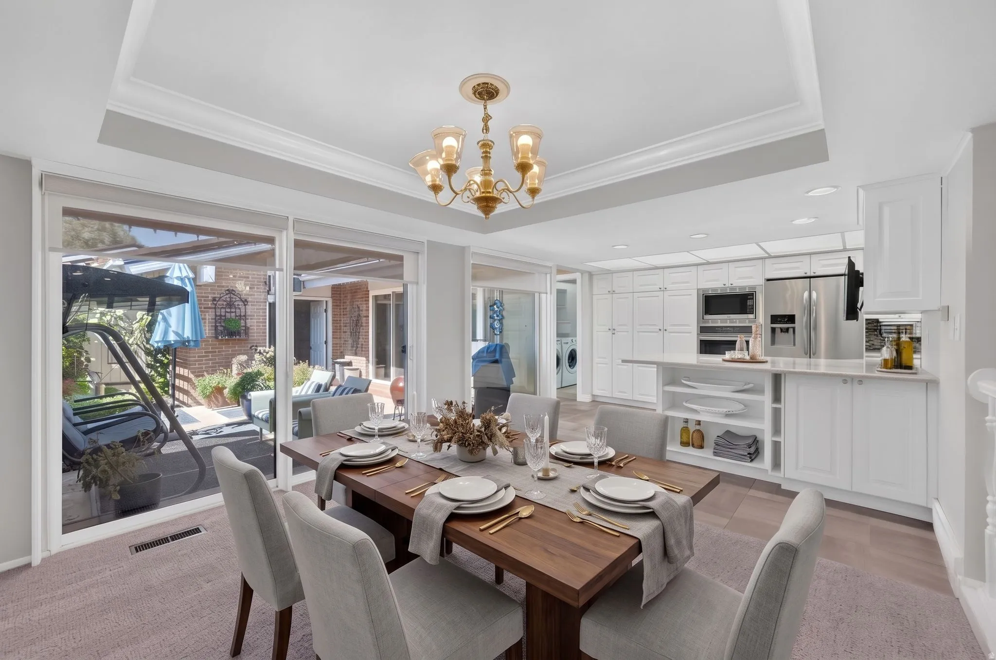 Recessed ceiling lighting, crown molding, a decorative chandelier, white cabinetry, and stainless-steel appliances