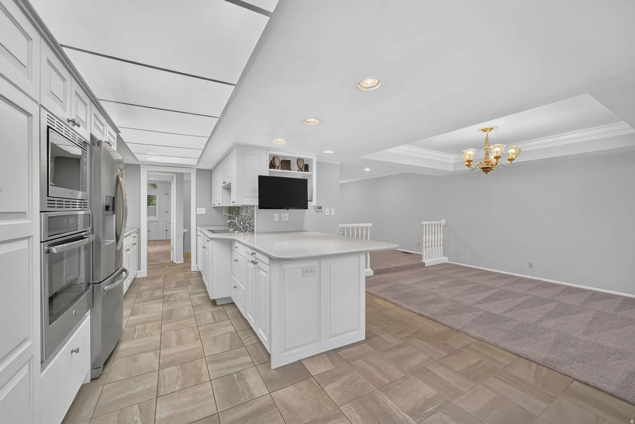 White shaker cabinetry with stainless steel appliances, tile flooring, and kitchen island with countertop seating