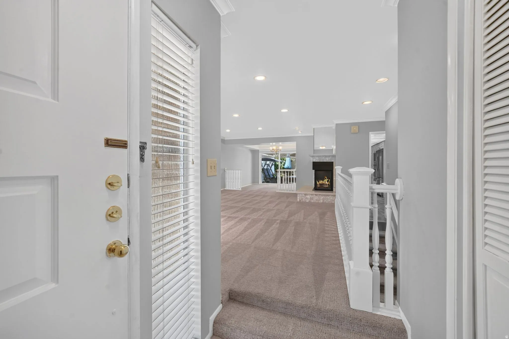 Bright hallway entry with white shaker-style cabinetry, brass hardware accents, and wood-finish flooring