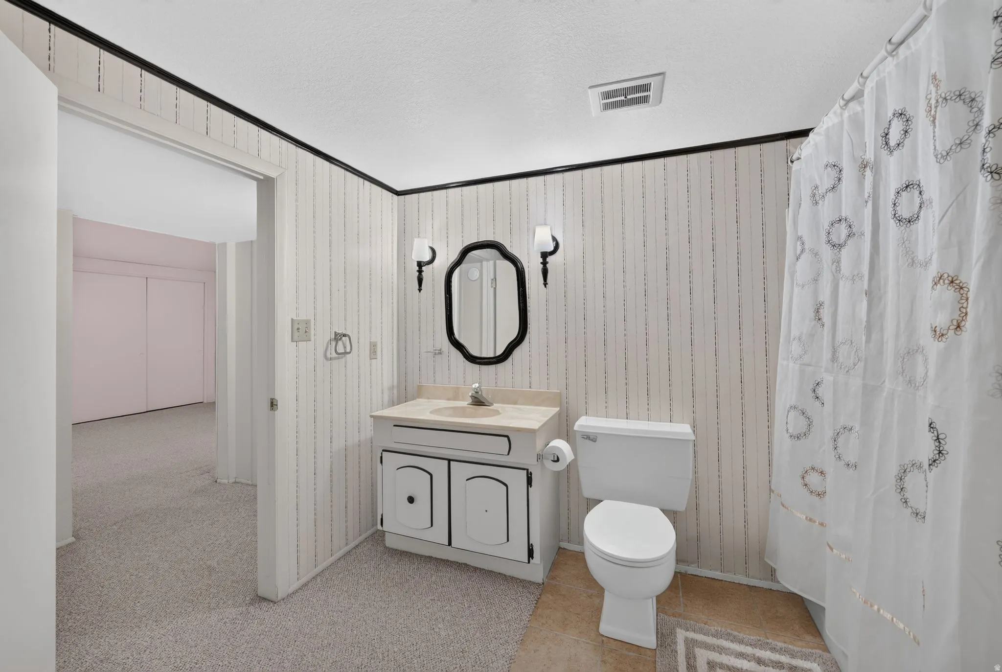 Vanity with integrated sink, wall-mounted sconce lighting, and an oval mirror
